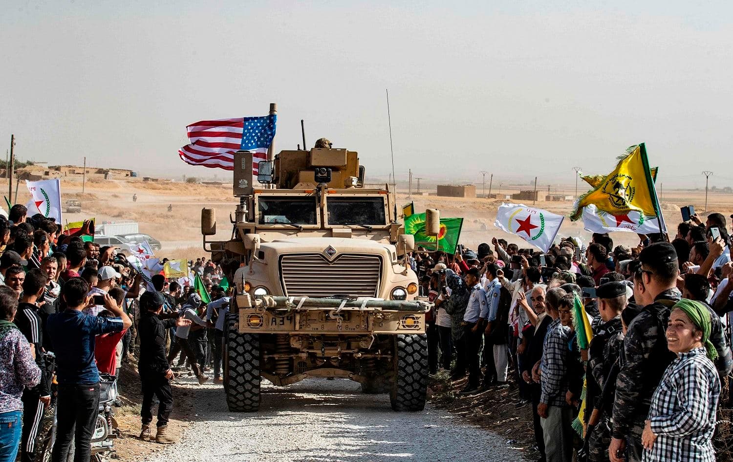Syrian Kurds gather around a US armoured vehicle during a demonstration against Turkish threats near the Turkish border, October 6, 2019. Photo: Delil Souleiman / AFP