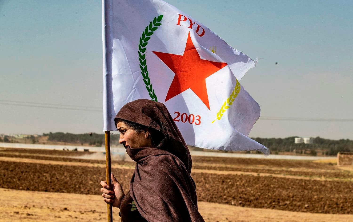 A Syrian Kurdish woman waves the flag of the Democratic Union Party (PYD) during a demonstration against Turkish threats in the town of Ras al-Ain in Syria's Hasake, near the Turkish border, October 6, 2019. Photo: Delil Souleiman / AFP