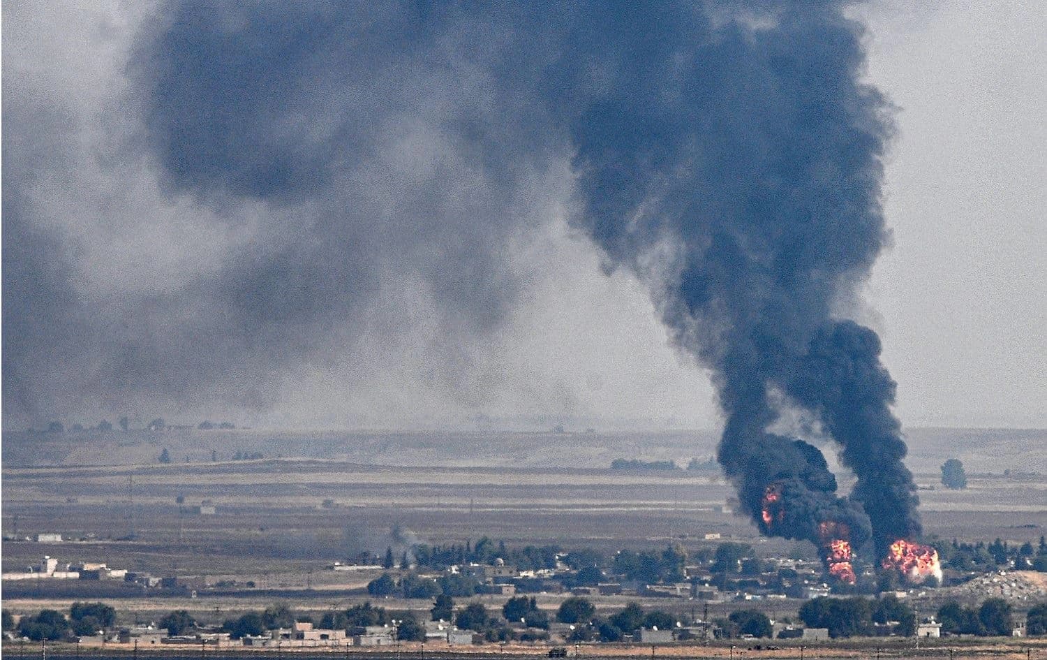 Smoke and fire rising from the Syrian town of Ras al-Ain during the Turkish offensive against Kurdish groups in northeastern Syria, October 17, 2019. Photo: Ozan Kose / AFP