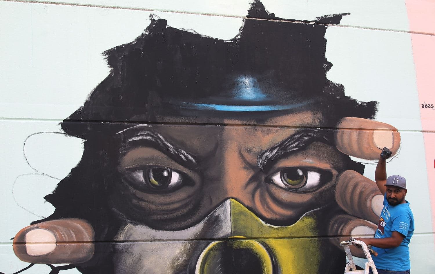 An Iraqi artist puts the final touches on a mural painting representing an anti-government protester wearing a mask in central Baghdad amid ongoing protests in the Iraqi capital on November 3, 2019. Photo: AFP / Ahmad al-Rubaye