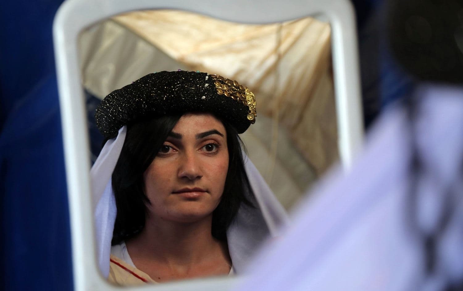 Iman Abbas, an 18-year-old Yezidi woman, gazes at herself in a mirror inside a tent at the Sharia IDP camp in Dohuk on November 21, 2019. Photo: AFP / Safin Hamed