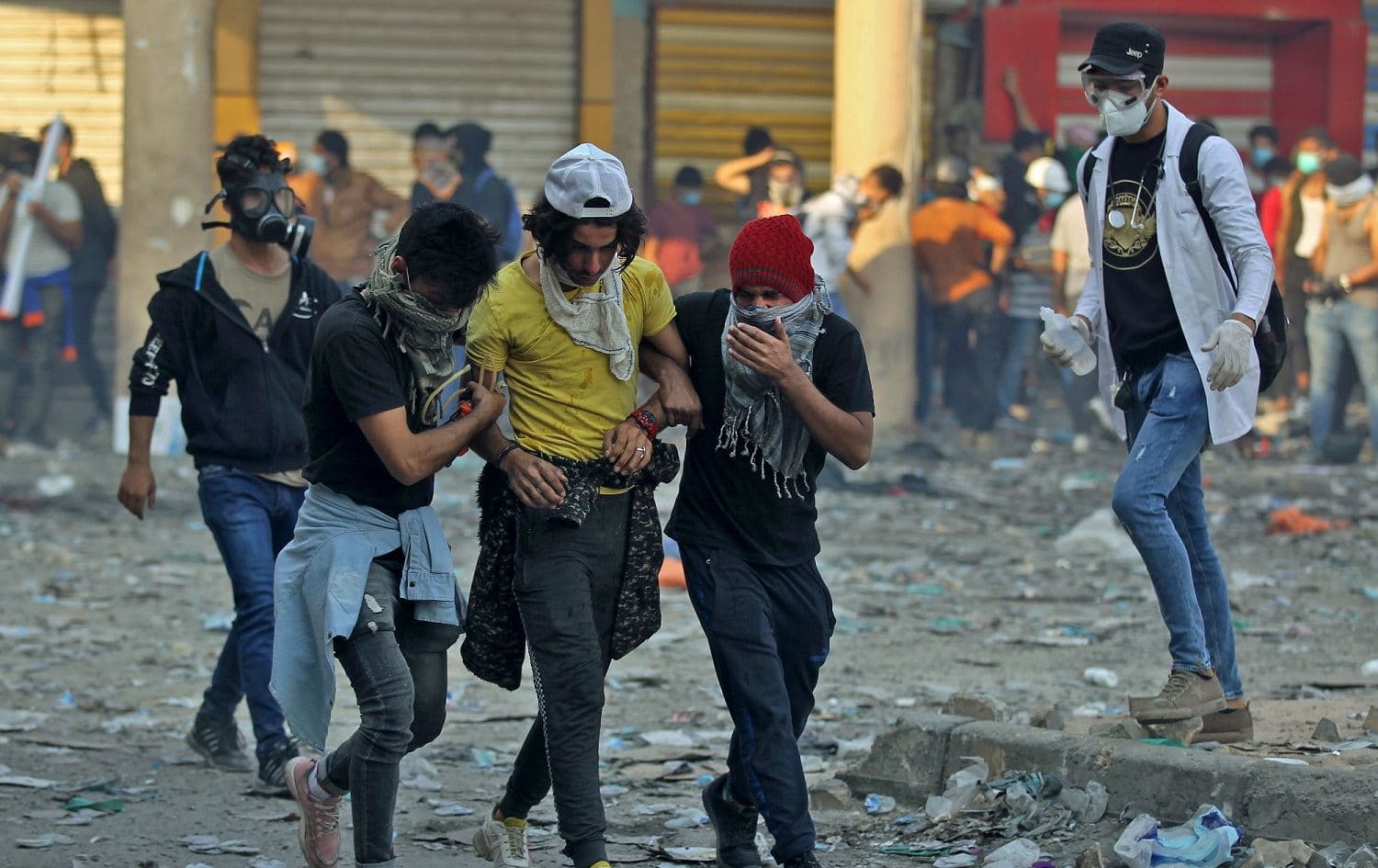Iraqi demonstrators help an injured youth amid clashes with security forces in the capital Baghdad's al-Rasheed street near al-Ahrar bridge, November 26, 2019. Photo: Ahmad al-Rubaye / AFP 