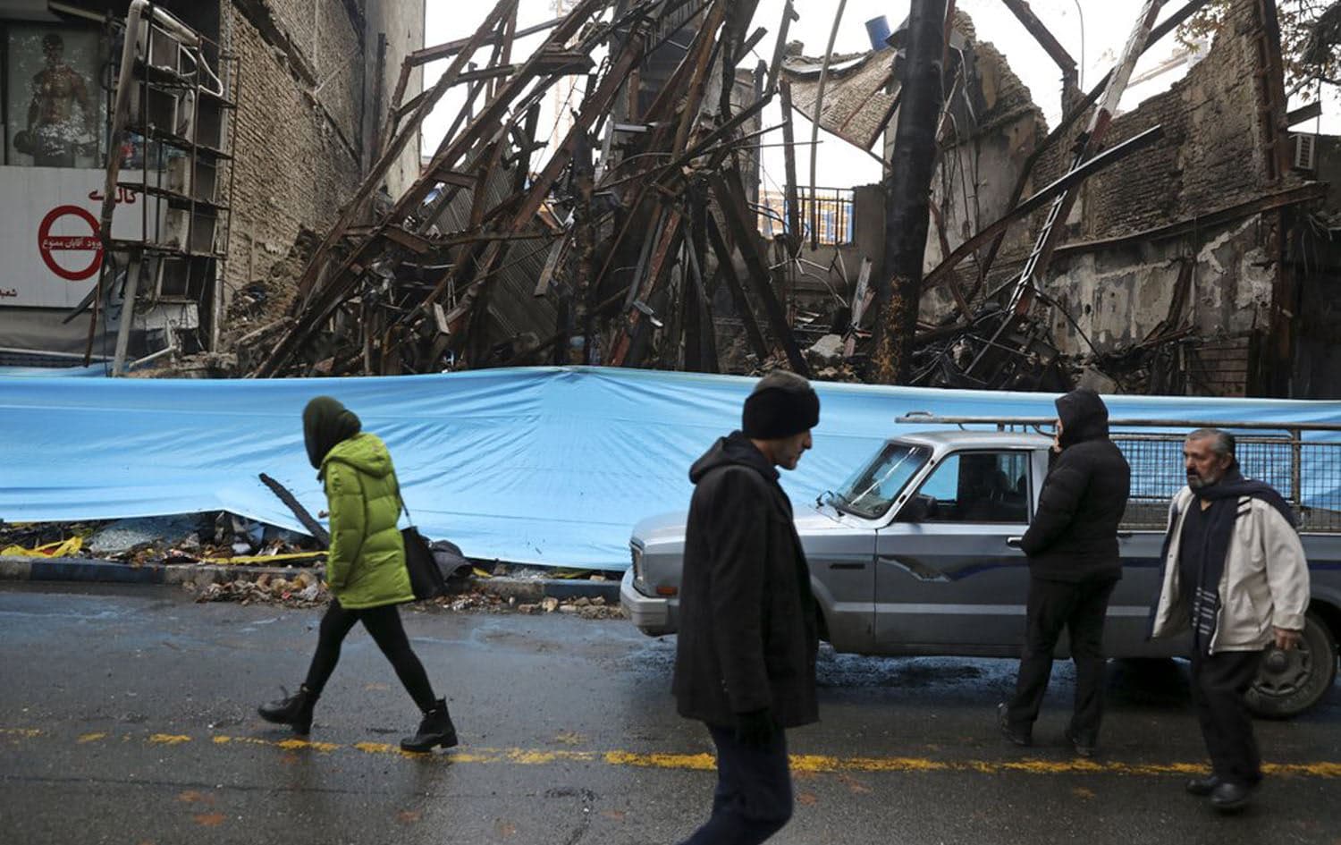 People walk past buildings burned during recent protests in Shahriar, Iran, November 20, 2019. File photo: Vahid Salemi / AP