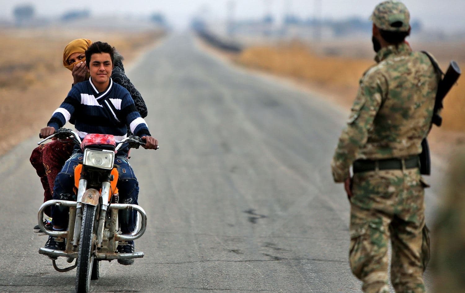 A Turkish-backed Syrian fighter mans a security checkpoint before an approaching motorcycle, along a road in the countryside outside Ain Issa, November 29, 2019. Photo: Bakr Alkasem / AFP