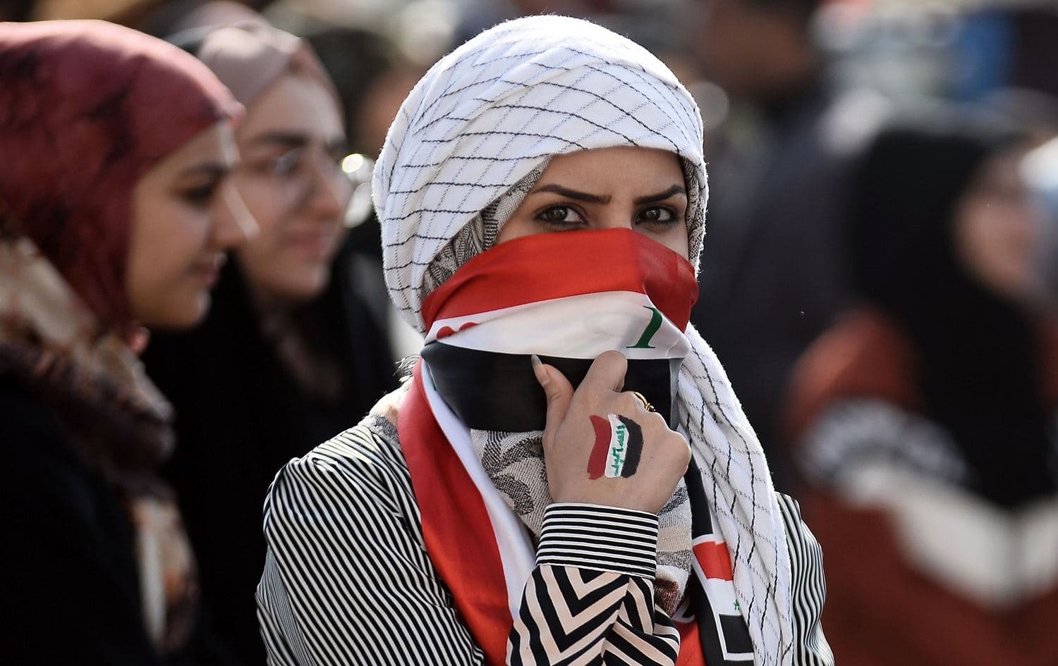An Iraqi student covers her face with a national flag as she takes part in an anti-government demonstration in Najaf on December 11, 2019. Photo: Haidar Hamdani/AFP