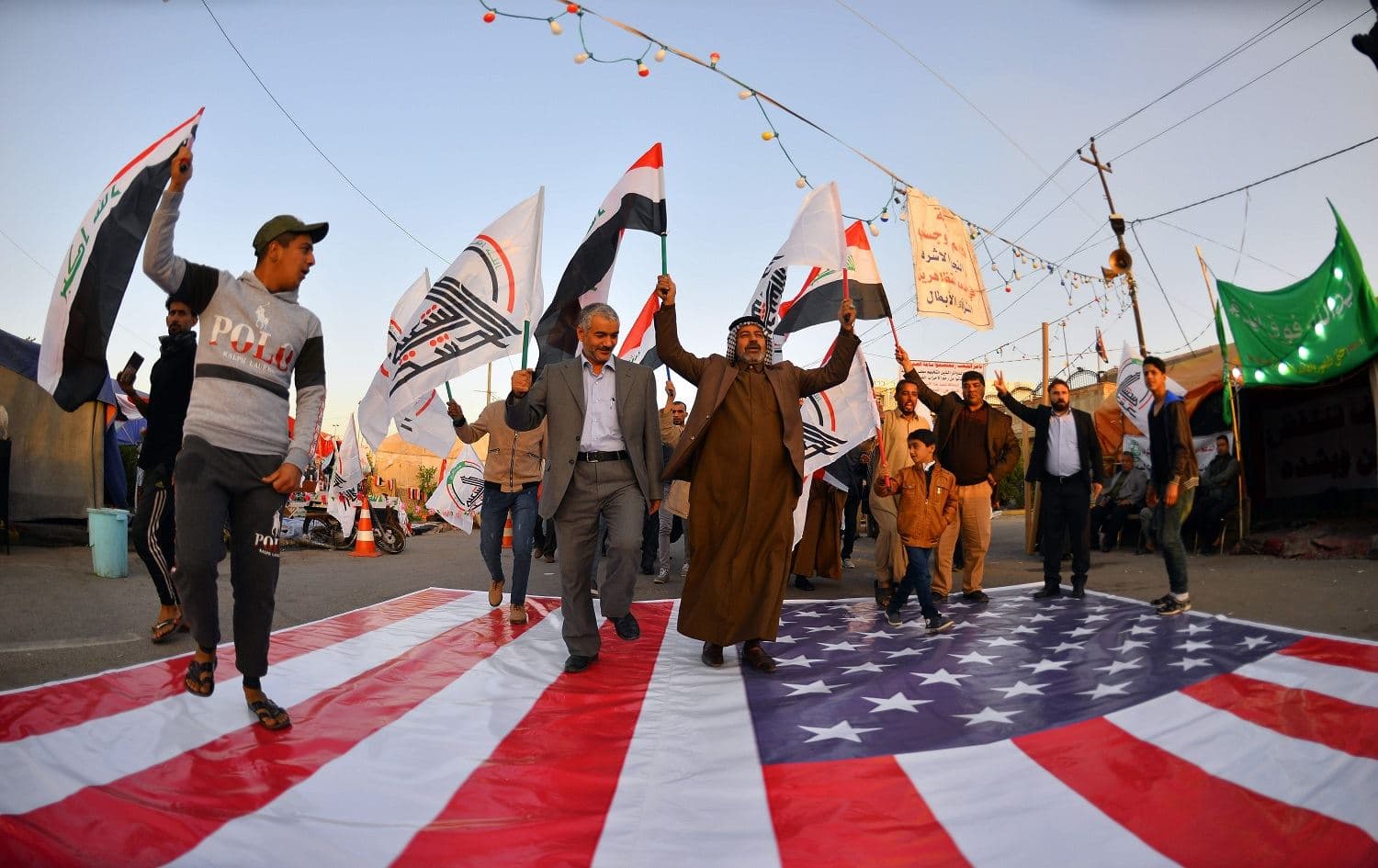 Iraqis in Najaf walk on a US national flag on December 30, 2019, during a demonstration to denounce the previous night's attacks by US forces in Al-Qaim. Photo: Haidar Hamdani/AFP