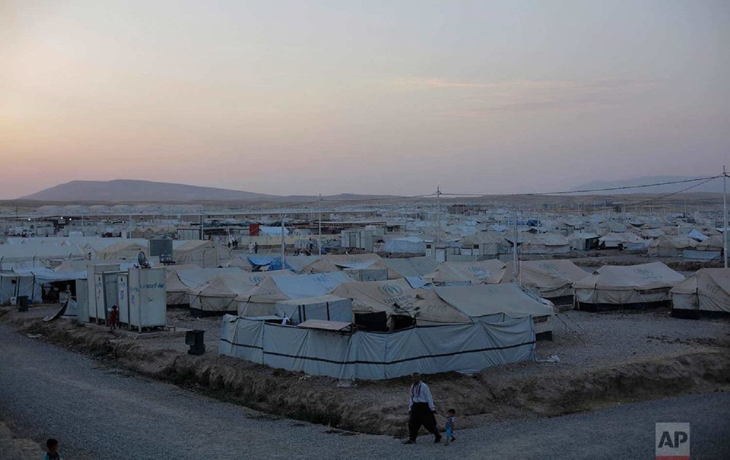 A man walks with a child through the Hassan Sham camp in Northern Iraq in August 2017. Photo: Bram Janssen/AP