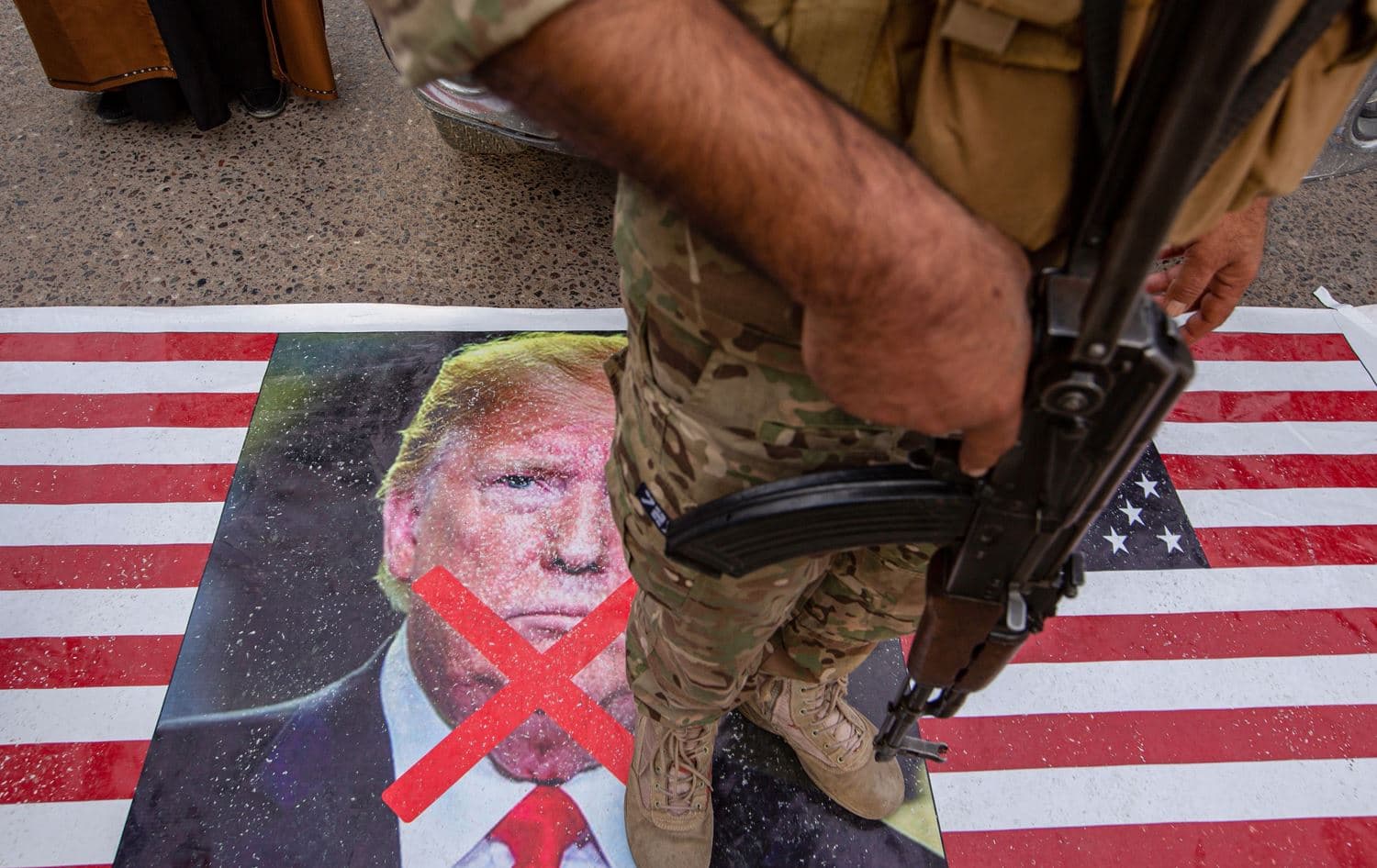 A member of Iraq's Hashed al-Shaabi paramilitary network stands on a US flag during a symbolic funeral procession for the network's deputy Abu Mahdi al-Muhandis in the southern city of Basra, on January 4, 2020. Photo: Hussein Faleh/AFP