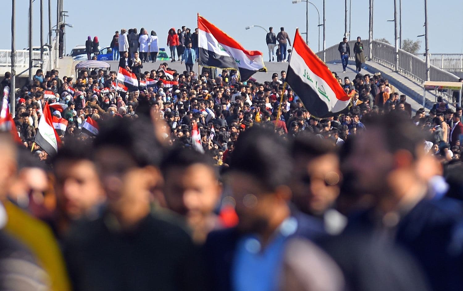 Iraqi students hold national flags during an anti-government demonstration in the central Iraqi city of Najaf on January 12, 2020. Photo: Haidar Hamdani / AFP