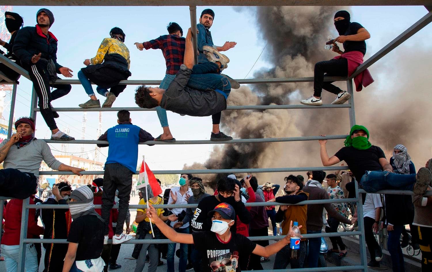 Anti-government protesters parkour up the metal beams of a former advertisement banner frame currently used as a make-shift roadblock during clashes with security forces in Iraq's southern city of Basra on January 20, 2020. Photo: Hussein Faleh / AFP