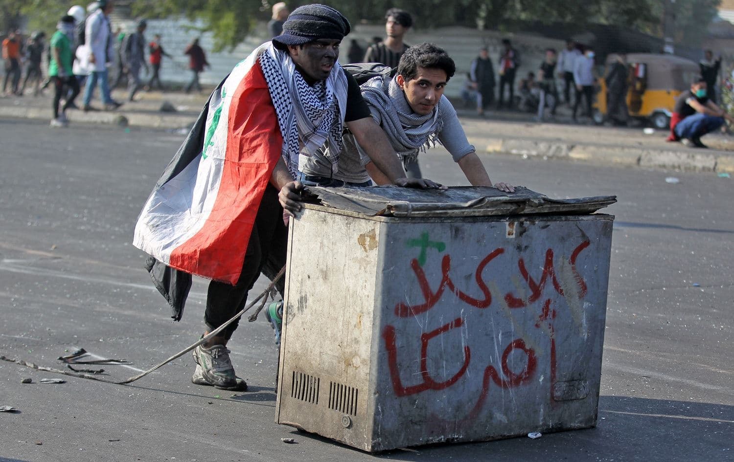 Iraqi protesters push a freezer with writing reading "No No America" amid clashes with riot police in Baghdad on January 20, 2020. Photo: Ahmad al-Rubaye/AFP