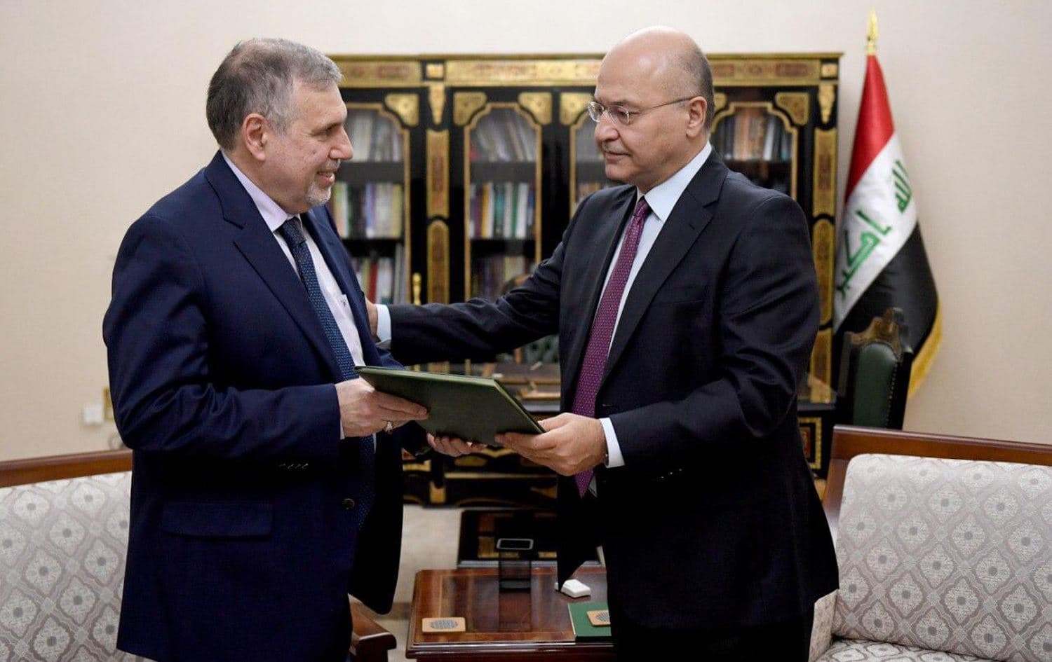 Iraqi President Barham Salih hands Mohammad Tawfiq Allawi an official letter granting the authority to form a new cabinet on February 1, 2020. (Photo via Iraqi state media)