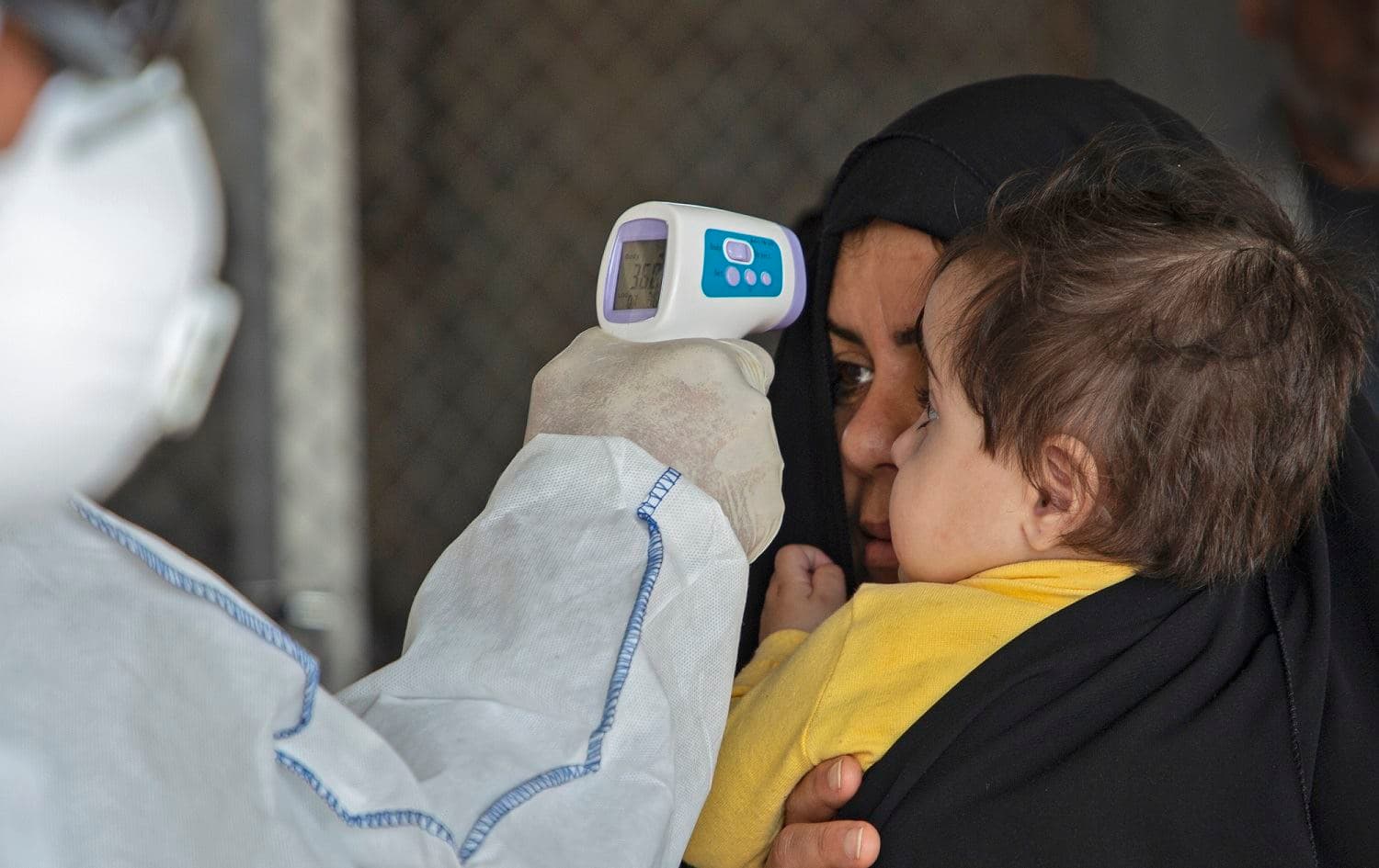 A member of a medical team takes a the temperature of an Iraqi traveller at the Shalamjah border crossing, some 15 kms southeast of the city of Basra, upon their return from Iran, February 21, 2020. Photo: Hussein Faleh / AFP