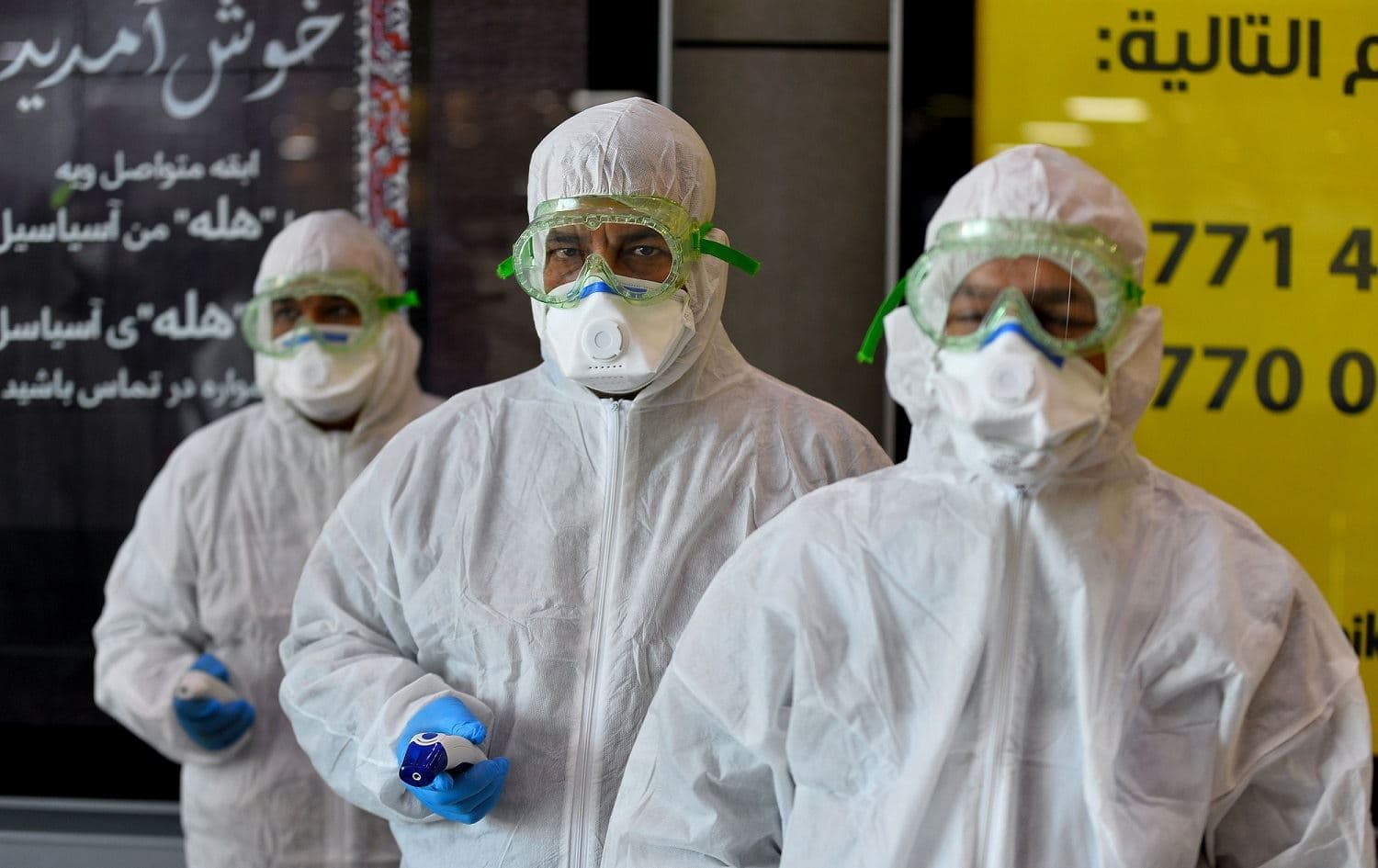 A medical team wearing protective outfits checks Iraqi passengers returning from Iran at Najaf International Airport, February 21, 2020. Photo: Haidar Hamdani / AFP