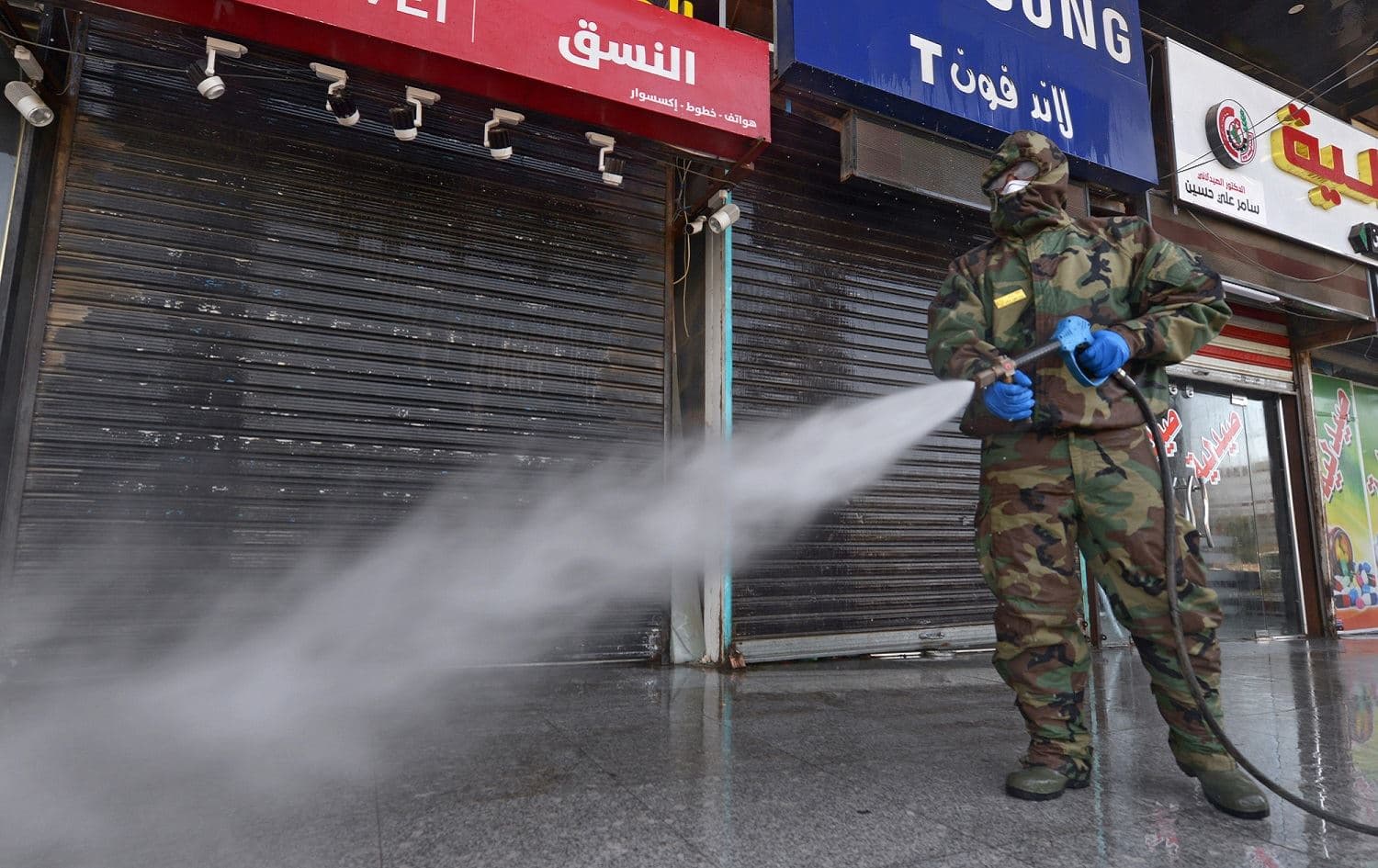 A member of the Iraqi civil defense sprays disinfectant on and around a building where Islamic students are quarantined for having had contact with Iraq’s first confirmed case of novel coronavirus infection, Najaf, February 26, 2020. Photo: Haidar Hamdani / AFP