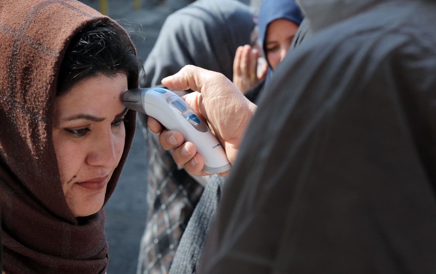 A medic checks the body temperature of travelers arriving at an Erbil checkpoint, March 2, 2020. Photo: Sadin Hamed / AFP