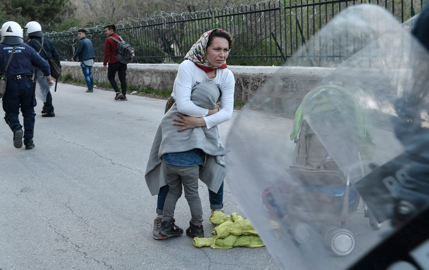 A woman protects her child while police disperse migrants outside the port of Mytilene on the Greek island of Lesbos on March 3, 2020. Photo: Louisa Gouliamaki/AFP 