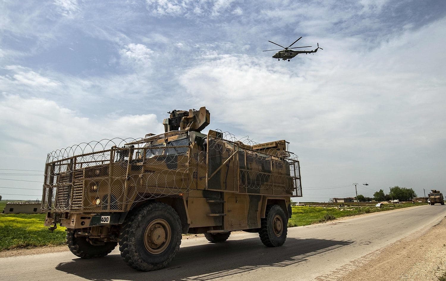 A Turkish military vehicle is accompanied on patrol by a Russian air force helicopter near Darbasiyah, northern Syria, April 22, 2020. Photo: Delil Souleiman / AFP 