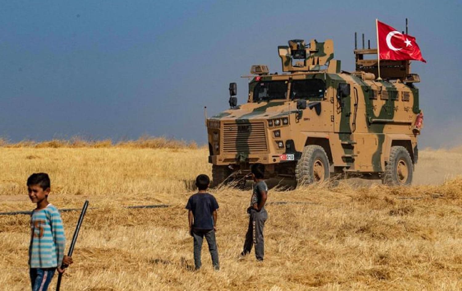 Children watch a Turkish military vehicle on patrol in the Syrian village of al-Hashisha, near Tal Abyad.  File photo: AFP 