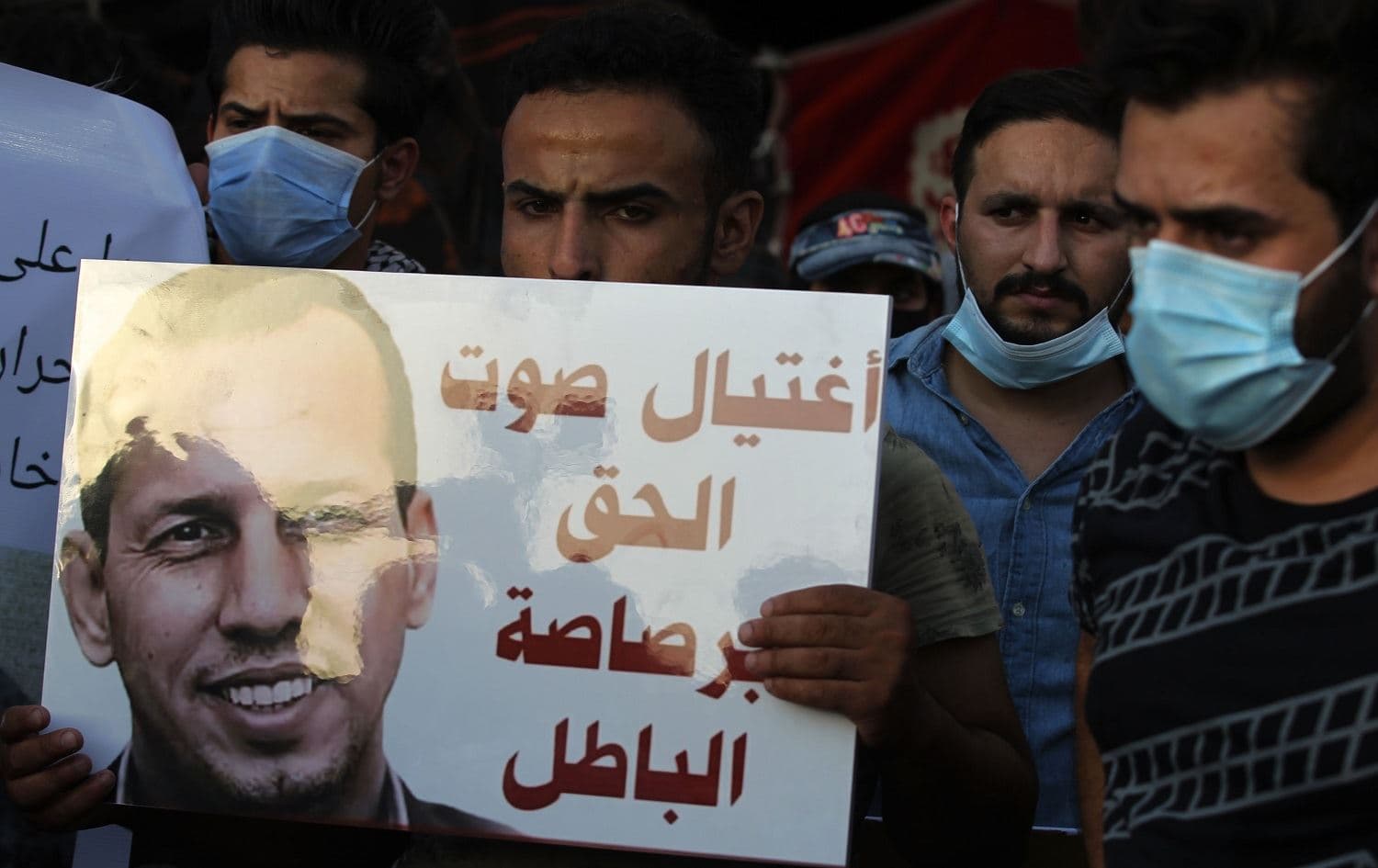 Iraqi demonstrators attend a symbolic funeral for Husham al-Hashimi on July 7, 2020 at Baghdad's Tahrir Square. Slogan reads in Arabic: "the voice of right killed with the bullet of wrong". Photo: Ahmad al-Rubaye / AFP