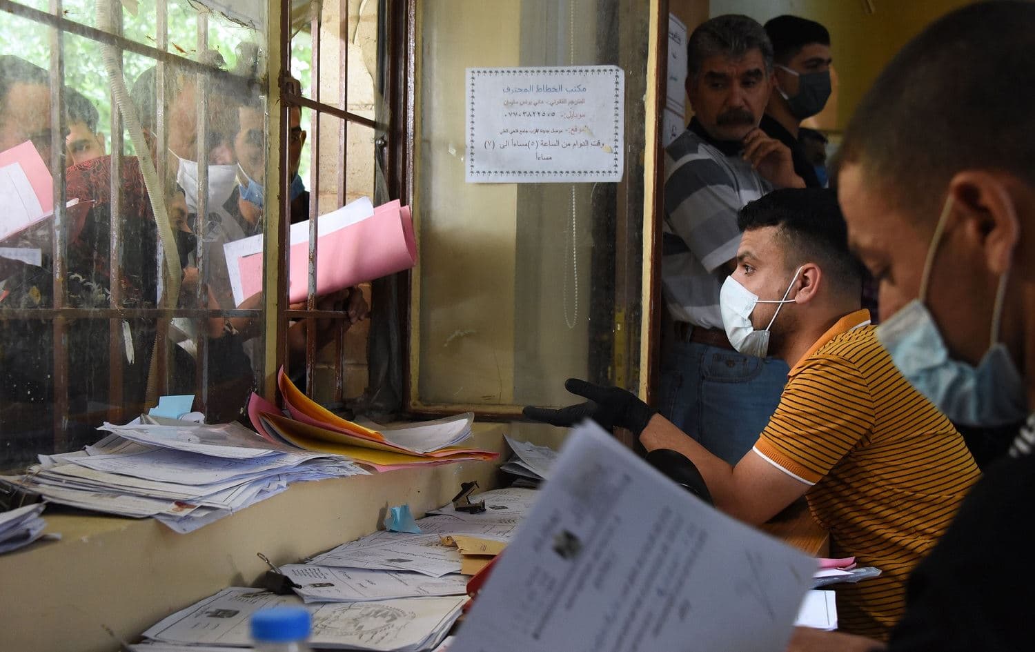 Iraqi employees at the general compensation department in Mosul speak to civilians waiting for their compensations following the destruction of their homes during the Battle of Mosul on June 15, 2020. Photo: Zaid al-Obeidi / AFP