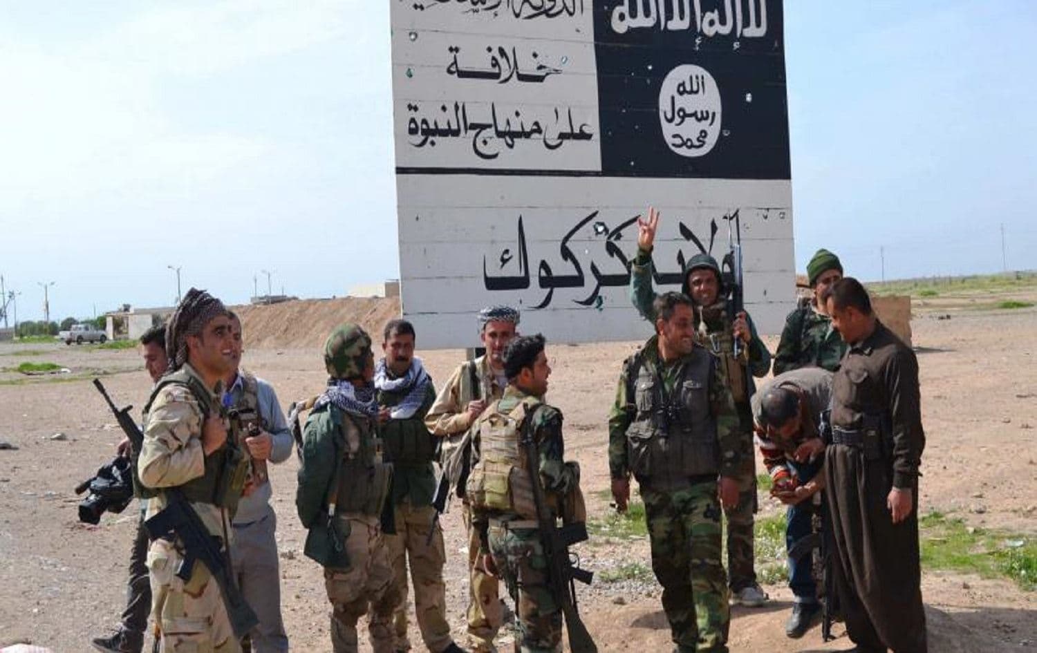 Peshmerga fighters stand next to an ISIS sign at the entrance to the town of Hawija, south of Kirkuk on March 9, 2015. Photo: AFP