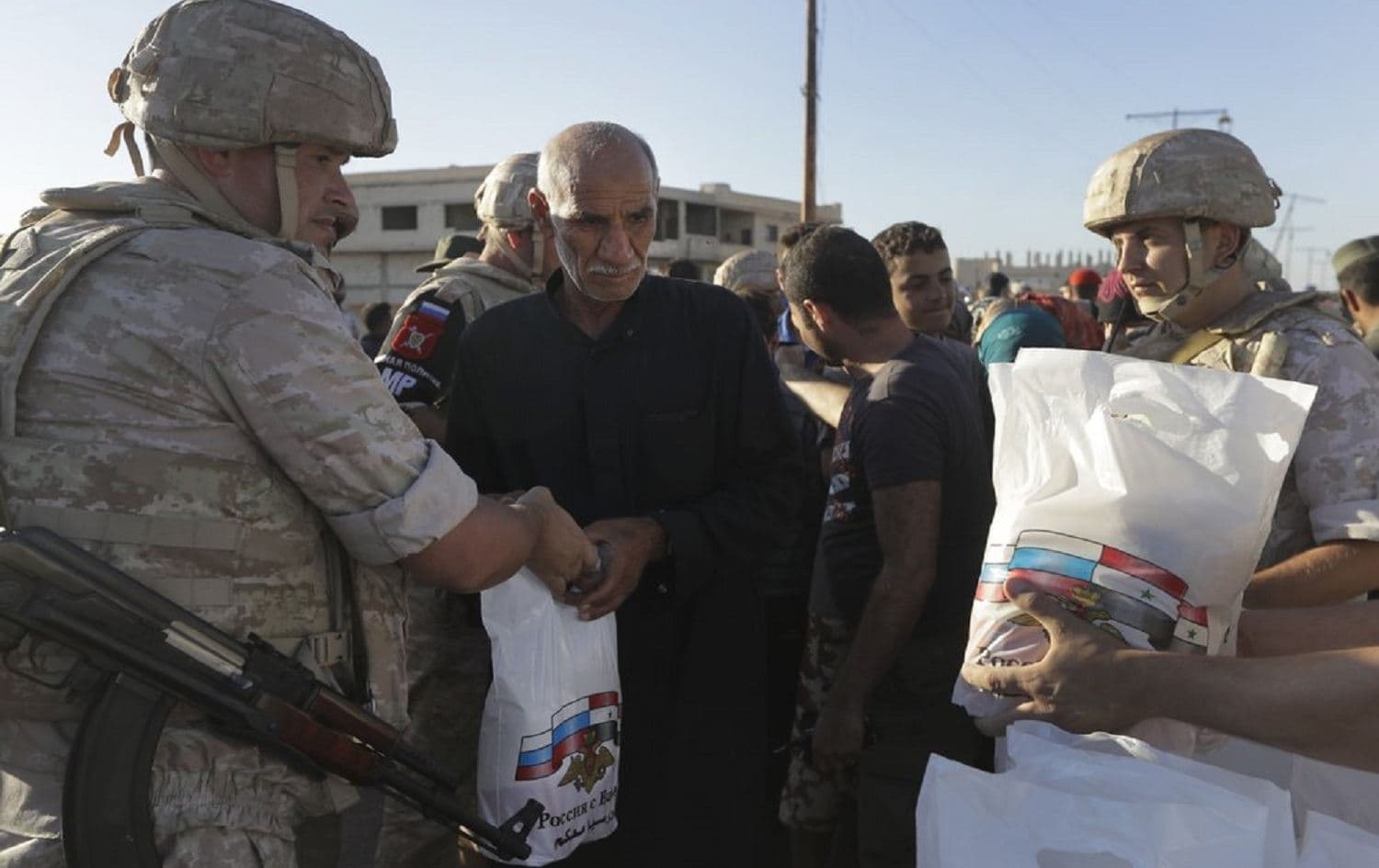 In this Aug. 15, 2018 file photo, local residents receive humanitarian aid from the Russian military in the town of Al-Rastan, Syria. Photo: Sergei Grits / AP