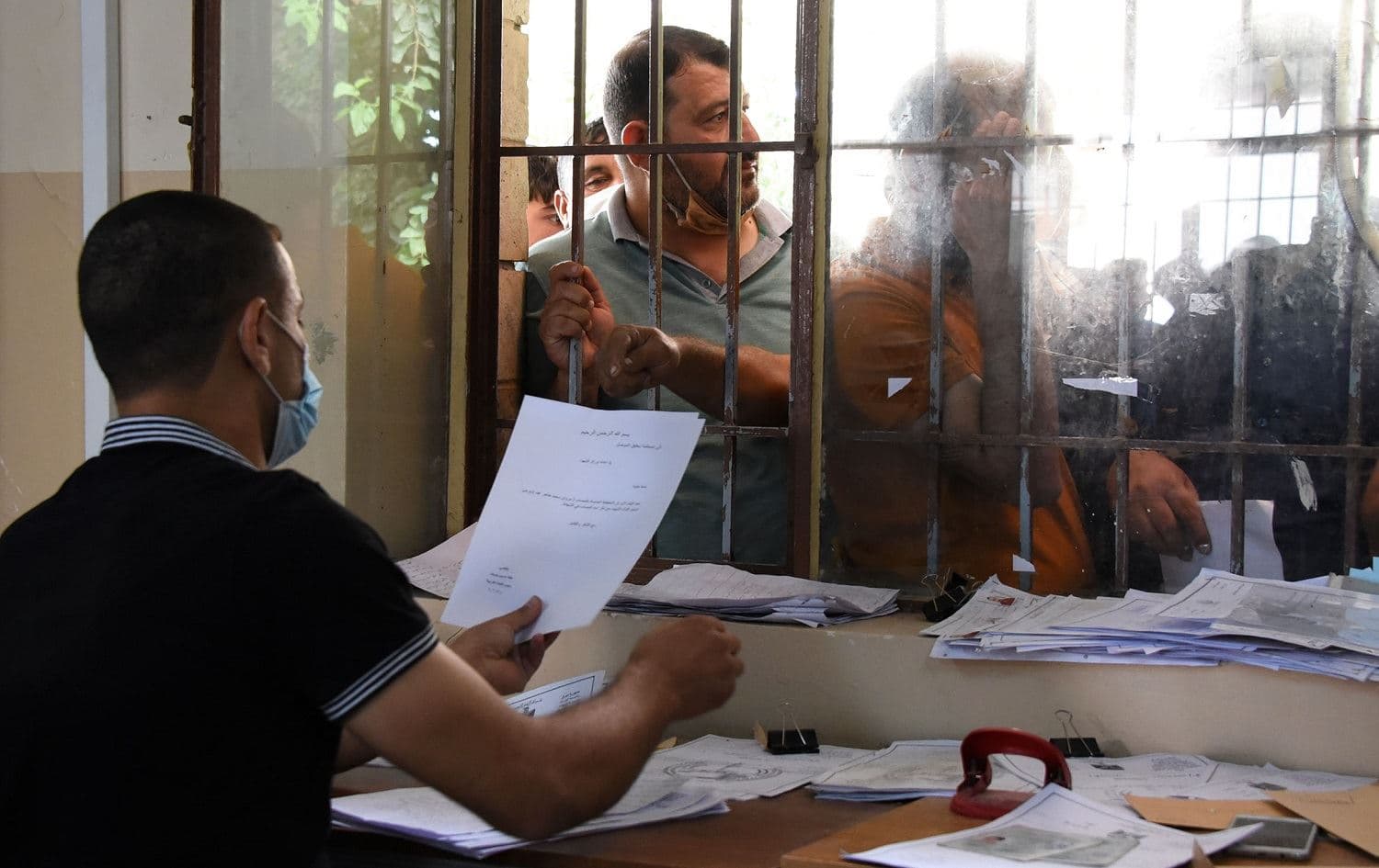 An Iraqi employee at the general compensation department in Mosul speaks to civilians on June 15, 2020. Photo: Zaid al-Obeidi / AFP