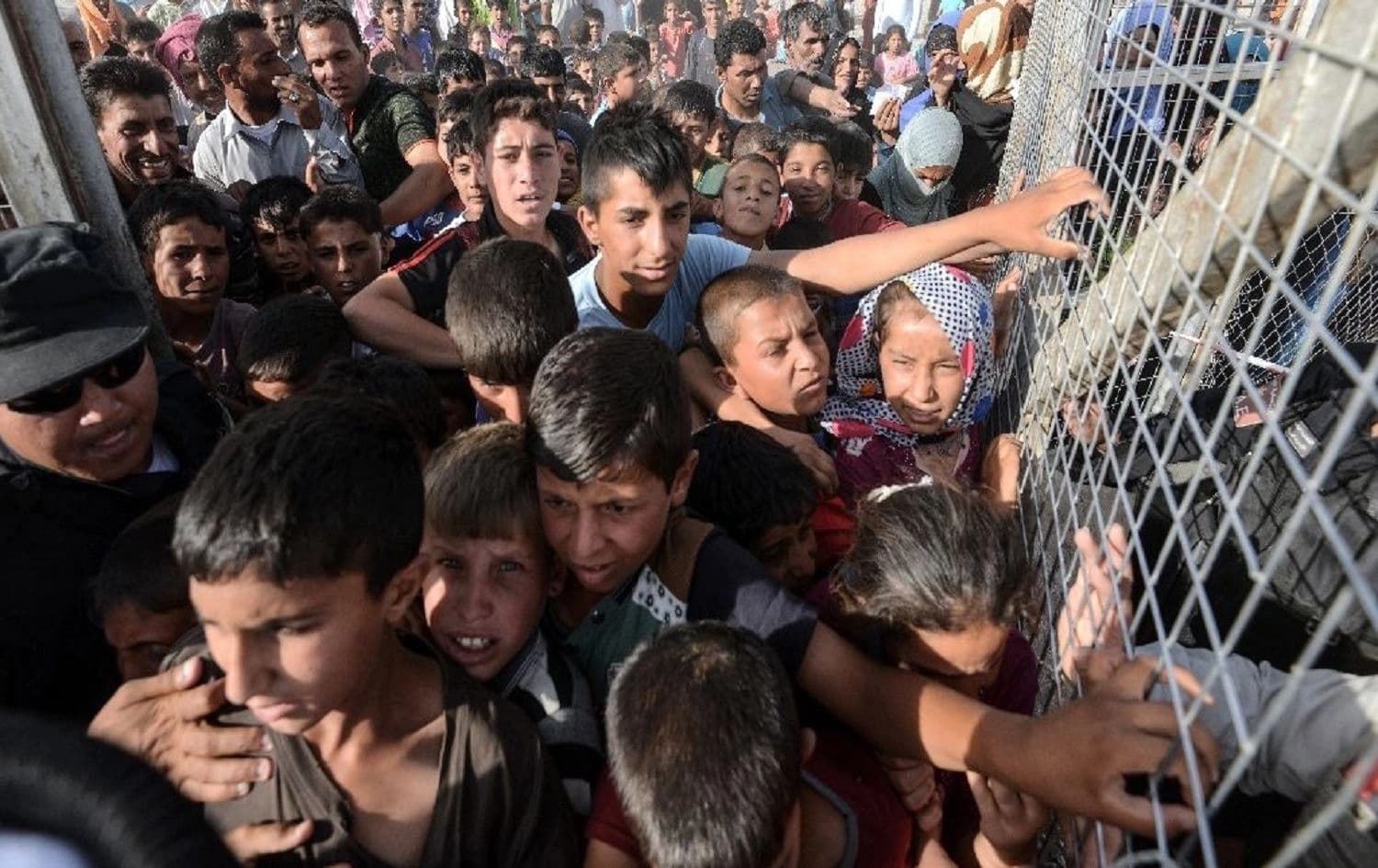 Displaced Iraqis queue behind a fence at the Hasansham IDP camp, 30 kilometres east of Mosul on June 10, 2017. Photo: Mohamed el-Shahed/AFP 