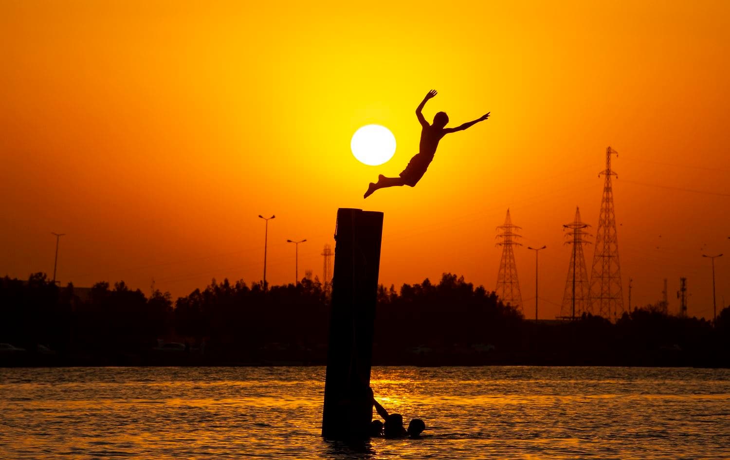 An Iraqi youth dives into the river in the Shatt Al-Arab river in the southern port city of Basra on August 6, 2020. Photo: Hussein Faleh / AFP