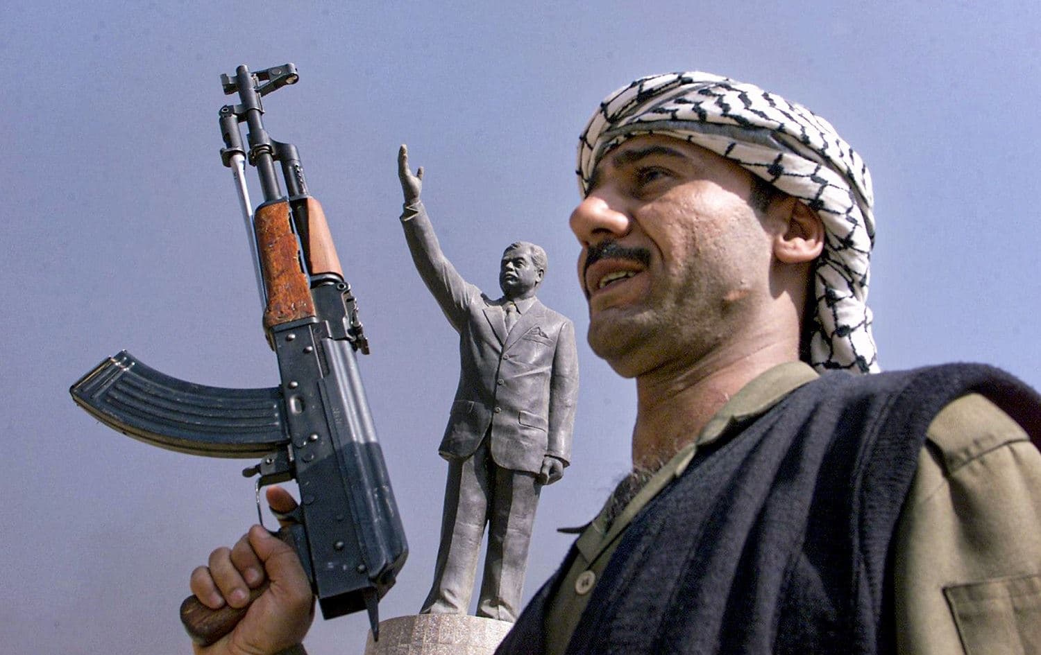 In this file photo taken on April 1, 2003, an armed member of Iraq's ruling Baath party stands in front of a statue of late president Saddam Hussein at Baghdad's al-Fardous square. Photo: Ahmad al-Rubaye/AFP