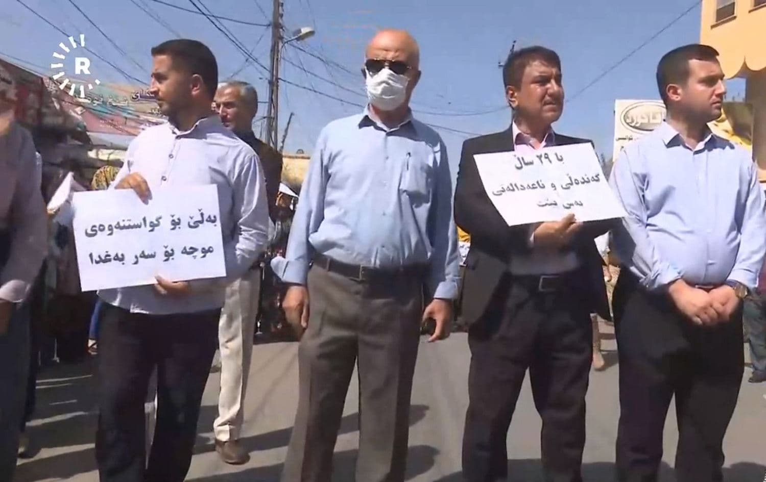 Striking teachers in Kalar hold up signs saying 'Yes for paying the salaries directly from Baghdad' and 'Let's stop the 29 years of corruption and inequality.' Photo: Rudaw