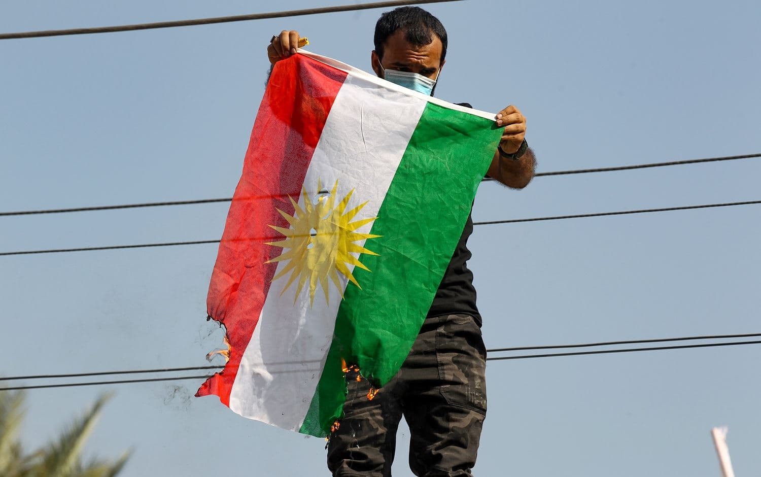 A Hashd al-Shaabi supporter burns a Kurdish flag during an attack by fellow protesters on the Kurdish Democratic Party's headquarters in Baghdad on October 17, 2020. Photo: Ahmad al-Rubaye / AFP