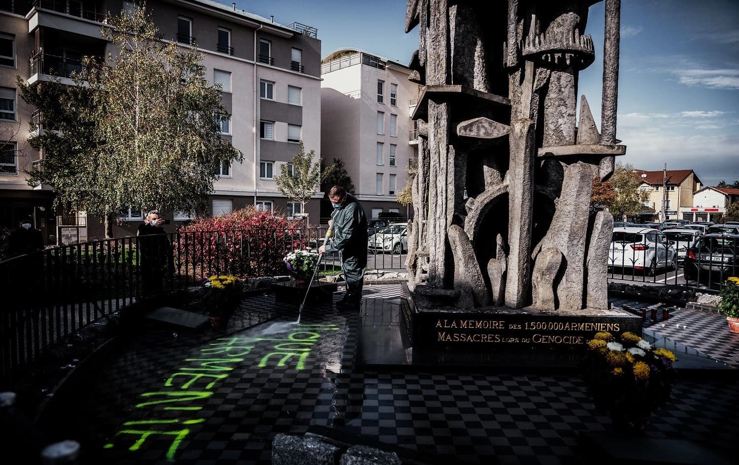 A man cleans the memorial for the Armenian genocide in Decines-Charpieu, near Lyon, on November 1, 2020. Photo: Jeff Pachoud/AFP