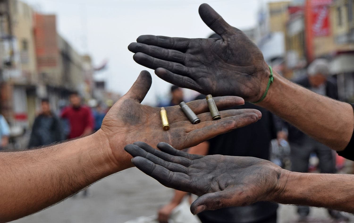Two men hold up spent bullet casings found at a protest site in Nasiriyah's Habboubi Square on  November 28, 2020. Photo: Asaad Niazi/AFP