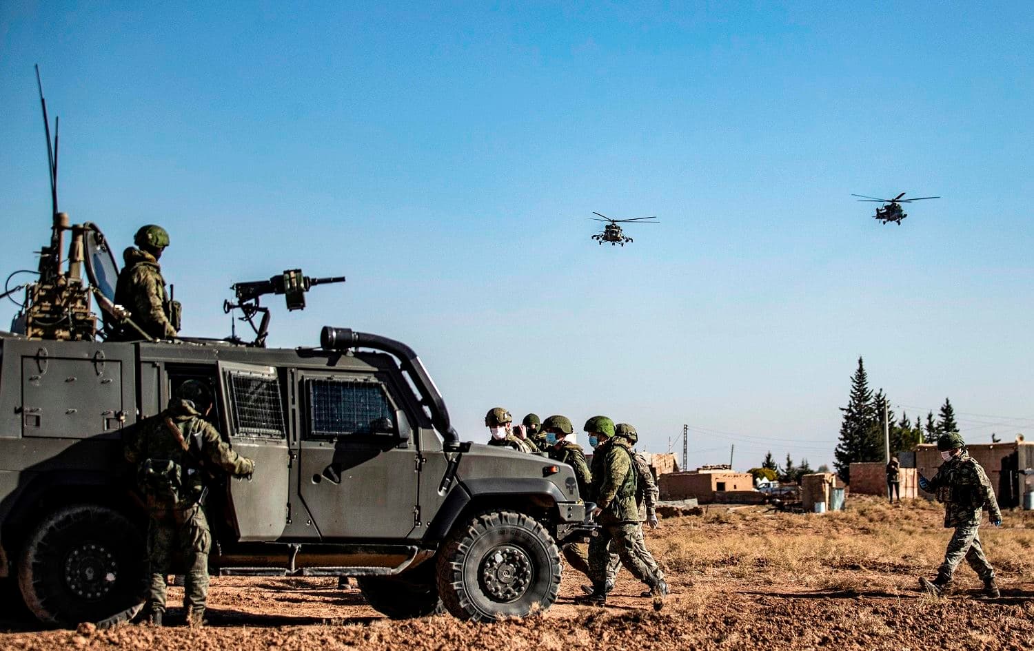 Russian military helicopters fly by soldiers and military vehicles during a joint Russian-Turkish patrol in the eastern countryside of the town of Darbasiyah near the border with Turkey in Syria's northeastern Hasaka province on December 7, 2020. Photo: Delil Souleiman/AFP