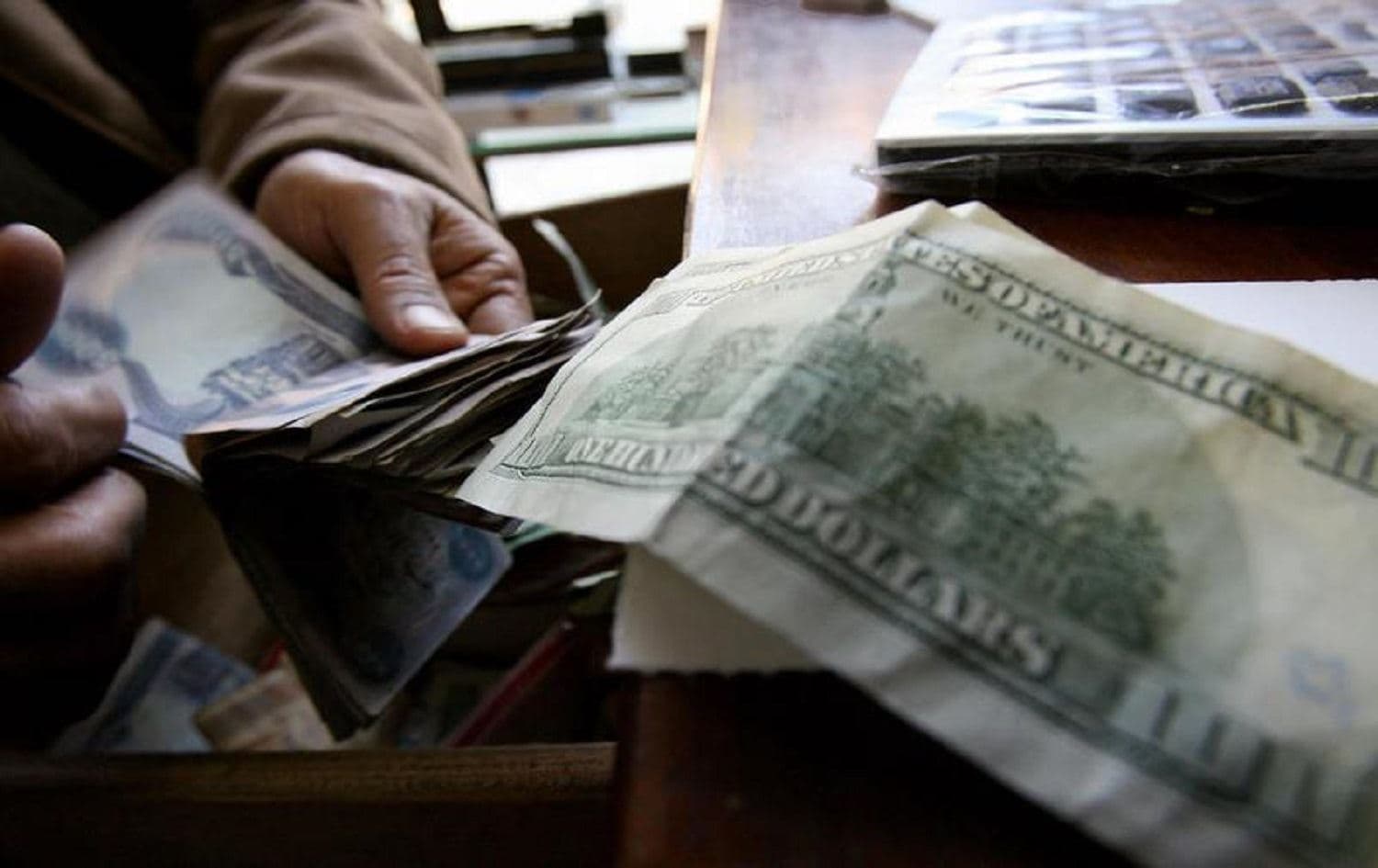 A man counts Iraqi Dinars as he exchanges them for US Dollars at his money exchange office in central Baghdad on 12 December 2007. File photo: AFP