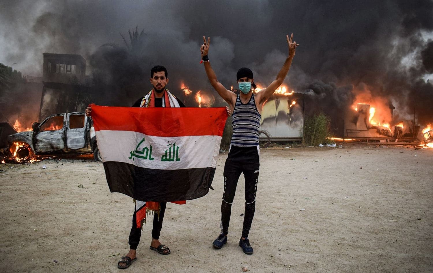 Protesters pose with a national flag during a demonstration outside the burning local government headquarters in Nasiriyah on Oct. 25, 2019. File photo: AFP