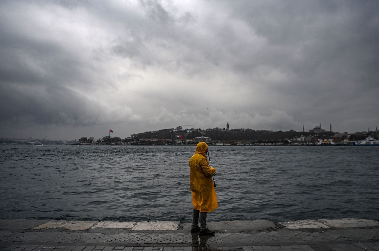 A man fishes on the shore of the Bosphorus strait on a rainy day at Karakoy port in Istanbul on March 19, 2021. Photo: Ozan Kose / AFP