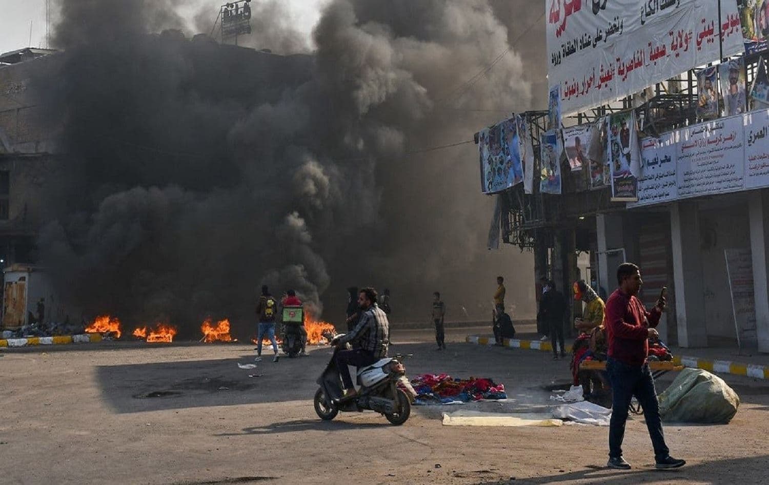 Iraqi protesters are pictured next to burning tires during clashes with police in the city of Nasiriyah on January 10, 2021. Photo: Asaad Niazi/AFP
