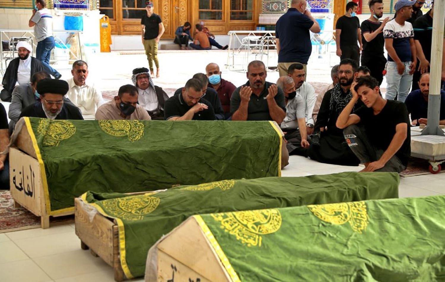 Mourners pray near the coffins of coronavirus patients who were killed in the Ibn al-Khatib hospital fire, during their funeral at the Imam Ali shrine in Najaf on April 25, 2021. Photo: AP / Anmar Khalil
