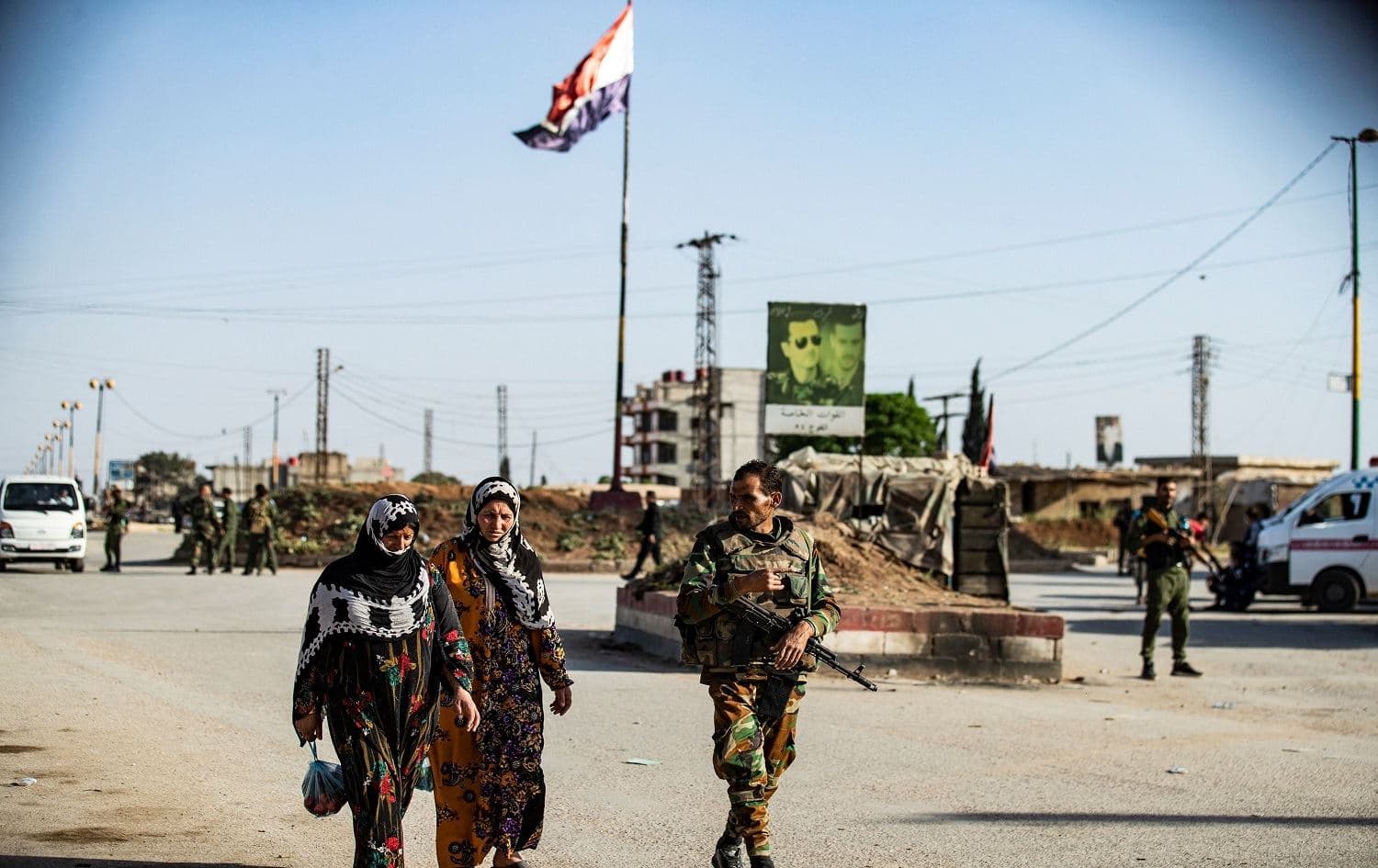 A member of Syrian government forces escorts women at a joint checkpoint with Kurdish forces in Qamishli on April 27, 2021. File photo: Delil Souleiman/AFP