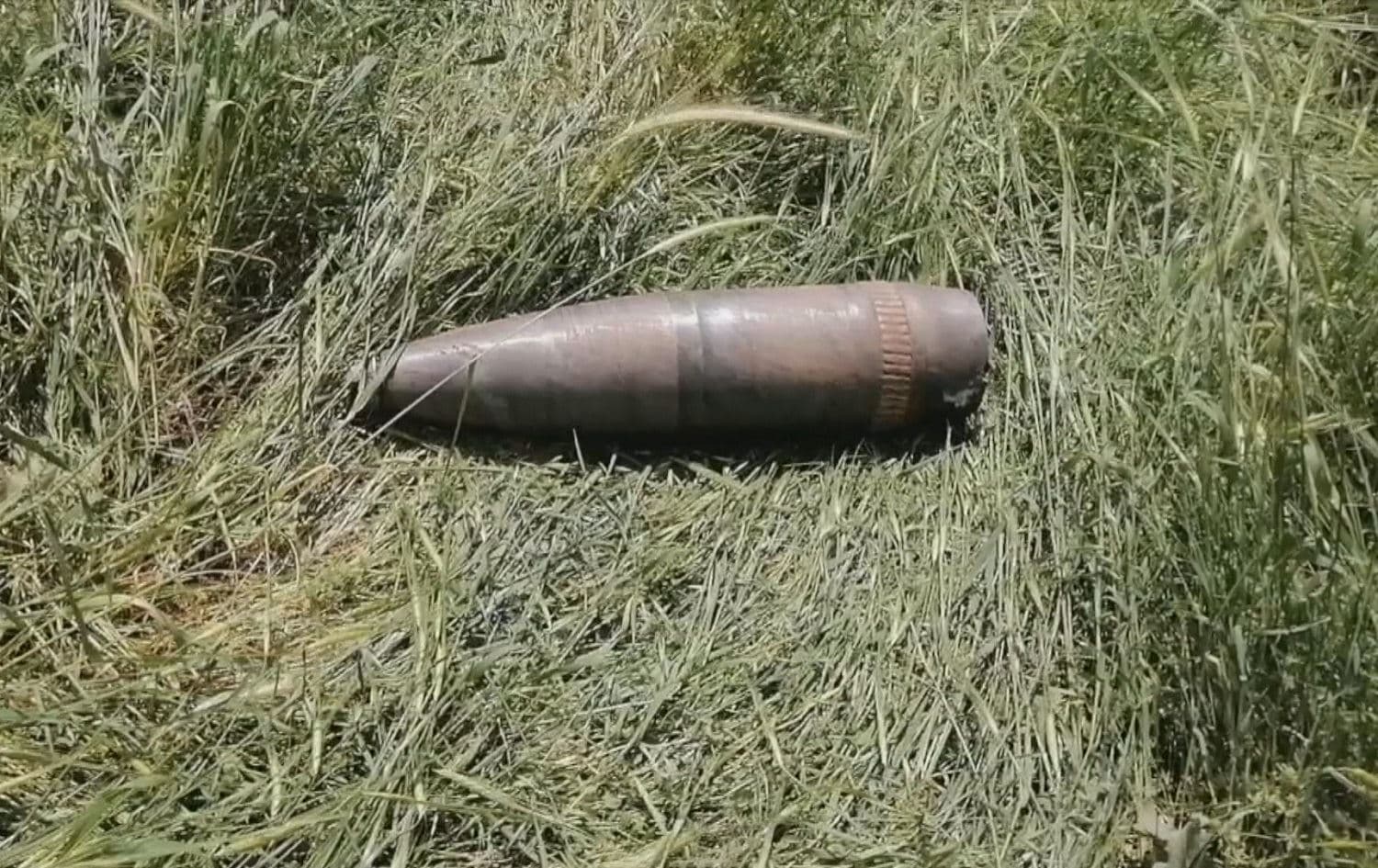 An unexploded Turkish artillery shell lies in the grass just 50 metres from houses in Chalke village, Duhok province on May 6, 2021. Photo: Rudaw