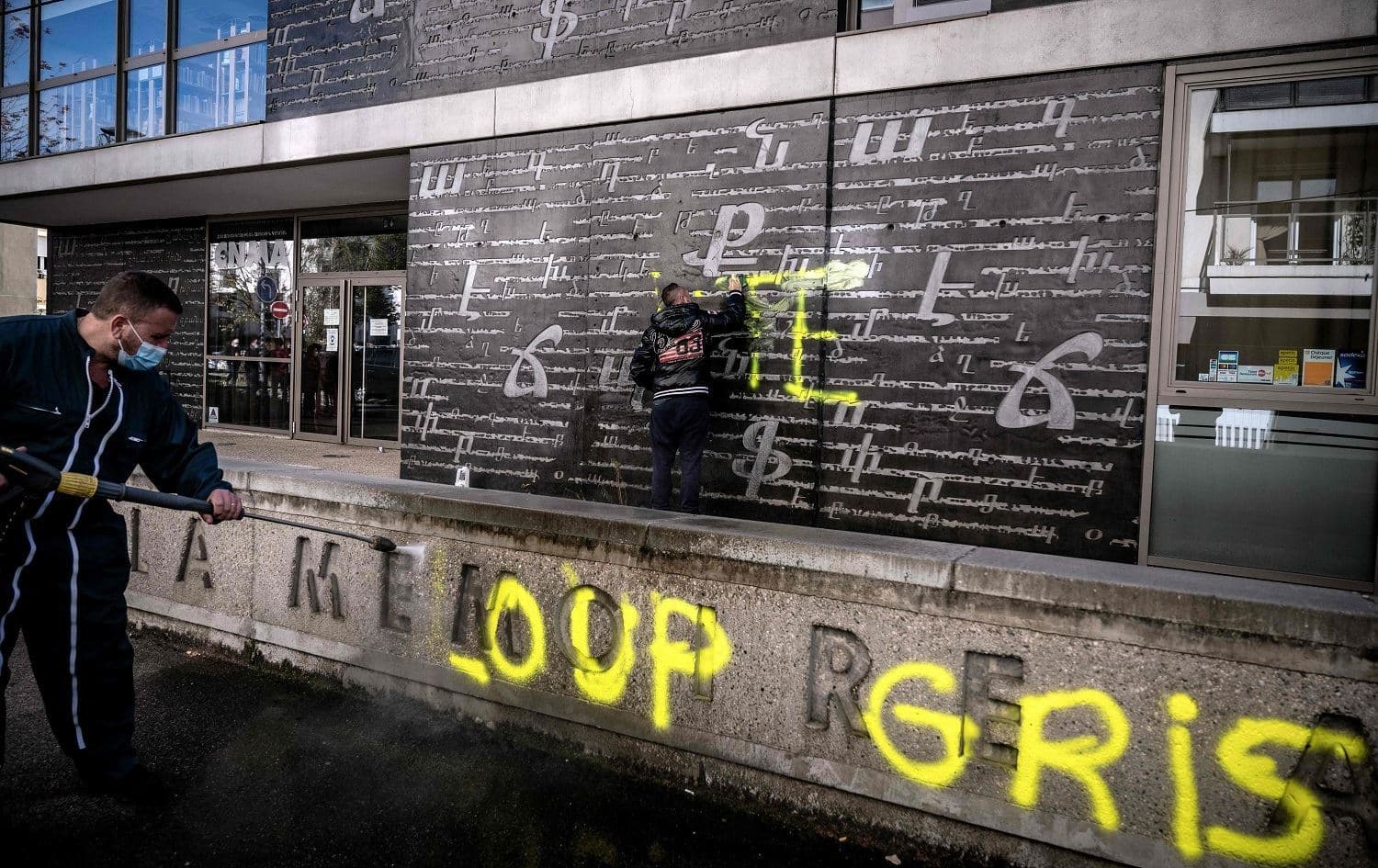 Men clean an outside wall of the National Armenian Memorial Centre in Decines-Charpieu near Lyon, France on November 1, 2020 where 'Loup Gris' [Grey Wolves] graffiti tags were painted overnight. Photo: Jeff Pachoud/AFP