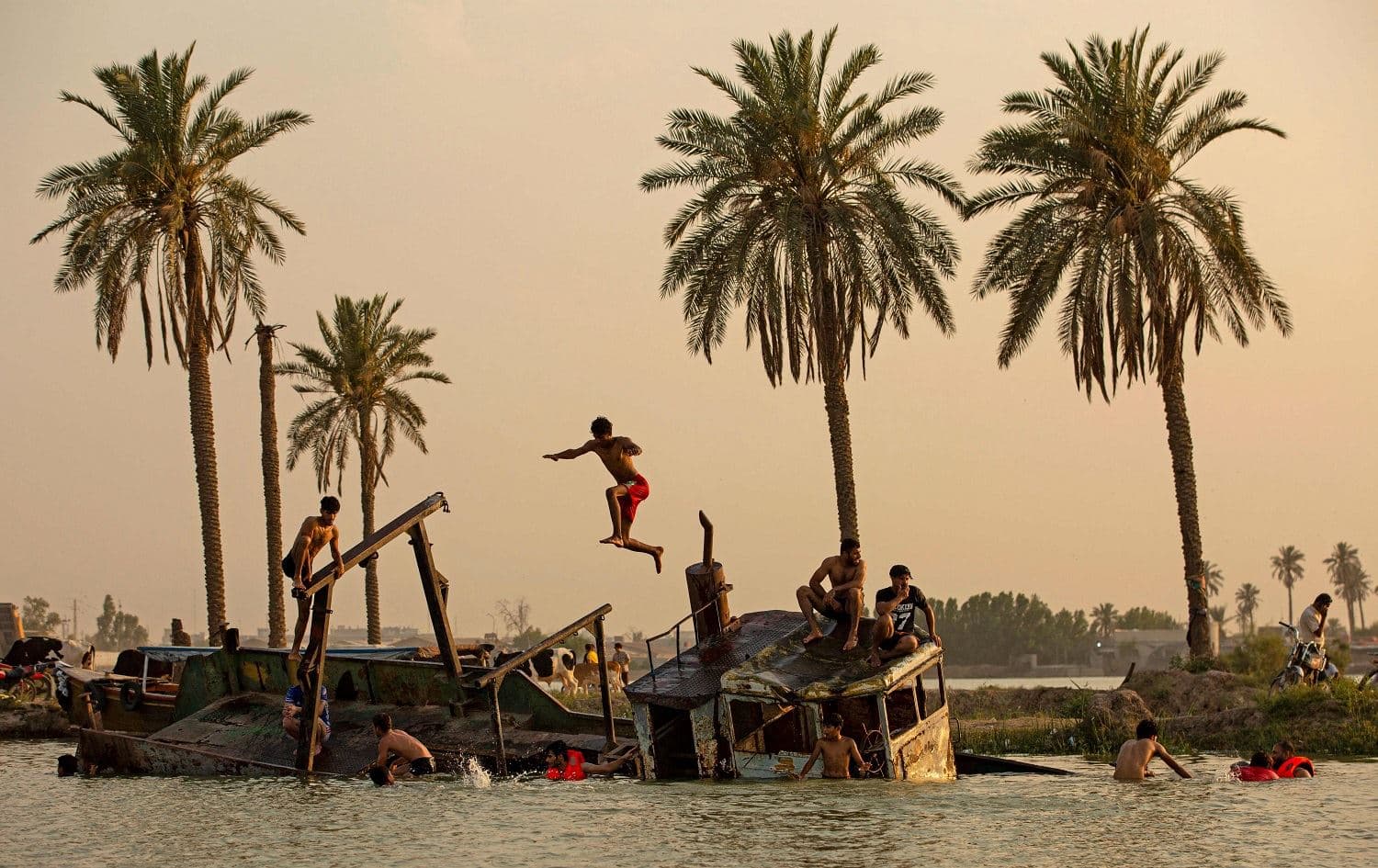 Iraqi youth swim in the Shatt Al-Arab river by the port of Maqil, Basra amid a heatwave in southern Iraq on June 29, 2021. Photo: Hussein Faleh/AFP