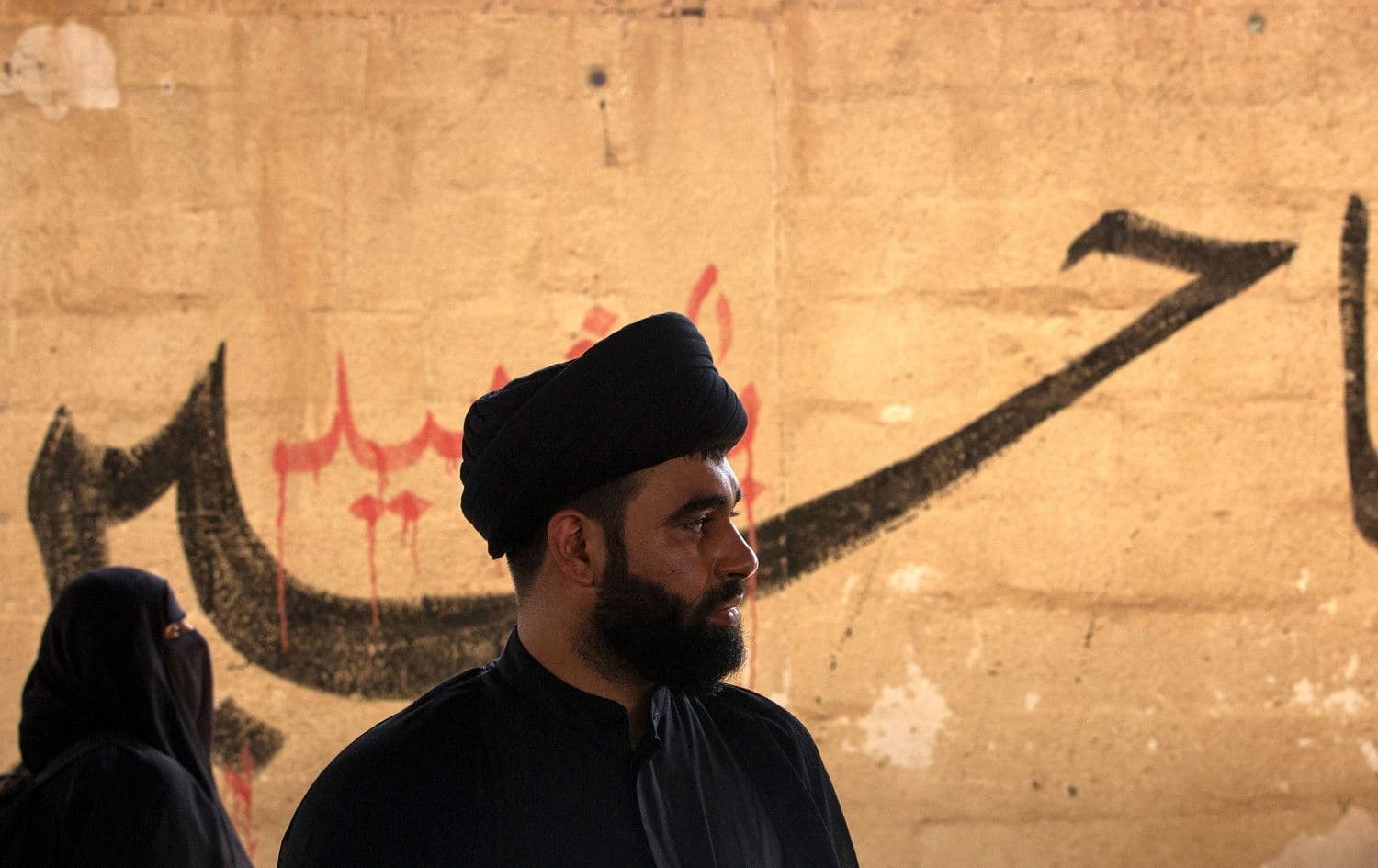 An Iranian cleric waits upon his arrival to Iraq via the al-Shalamija border crossing west of Basra before starting his journey toward the holy city of Karbala to mark the Arbaeen religious festival, on September 25, 2021. Photo: Hussein Faleh/AFP