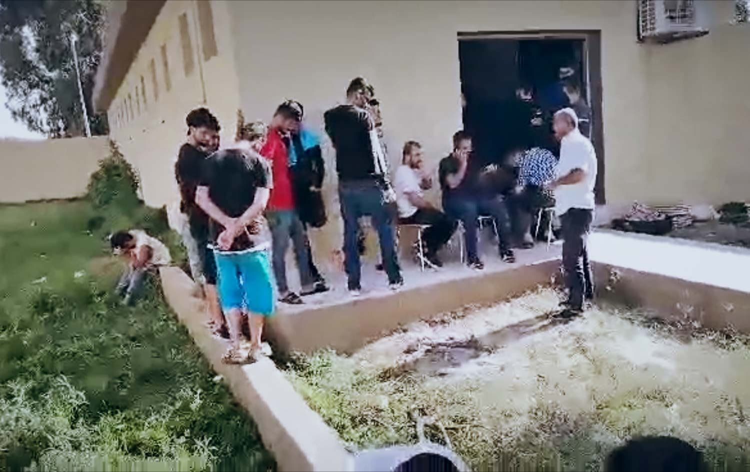 Migrants line up to make phone calls in police custody in Libya's Benghazi. Photo: Screengrab from a video submitted to Rudaw