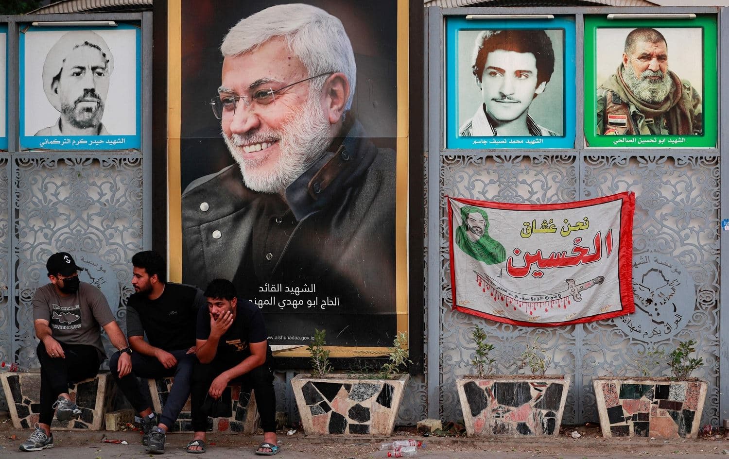 Supporters of the pro-Iran Hashd al-Shaabi alliance rest in front of posters of killed protesters as well as a portrait of slain Iraqi commander Abu Mahdi al-Muhandis (second from left) outside Baghdad's Green Zone on October 20, 2021. Photo: Ahmad al-Rubaye/AFP