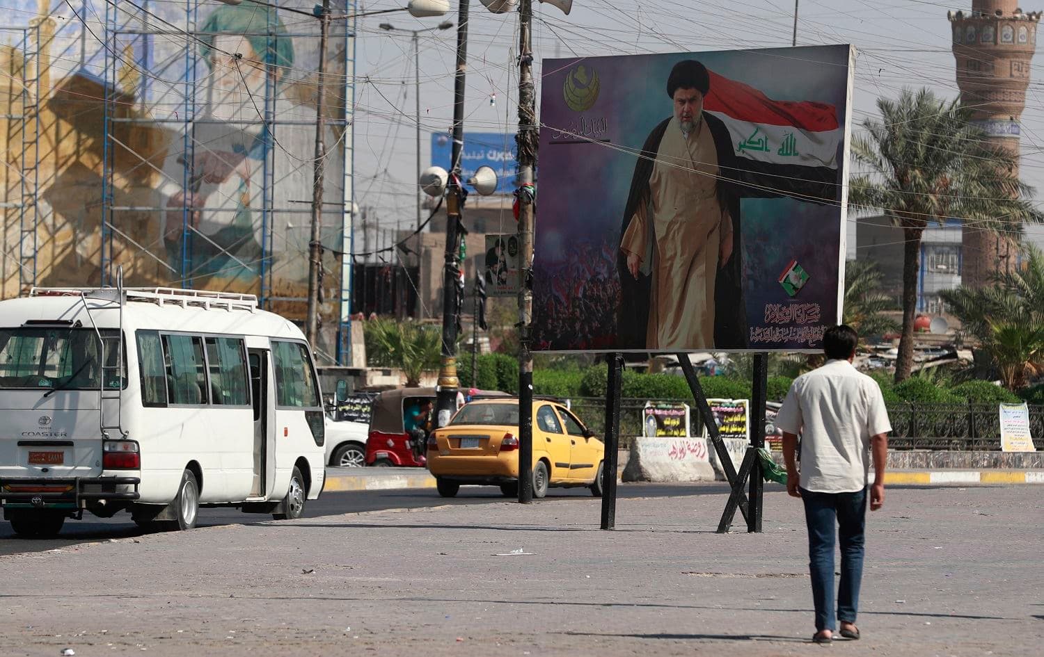 Iraqis pass by a poster of Shiite cleric Muqtada al-Sadr in Sadr City in Baghdad on October 17, 2021. Photo: AFP