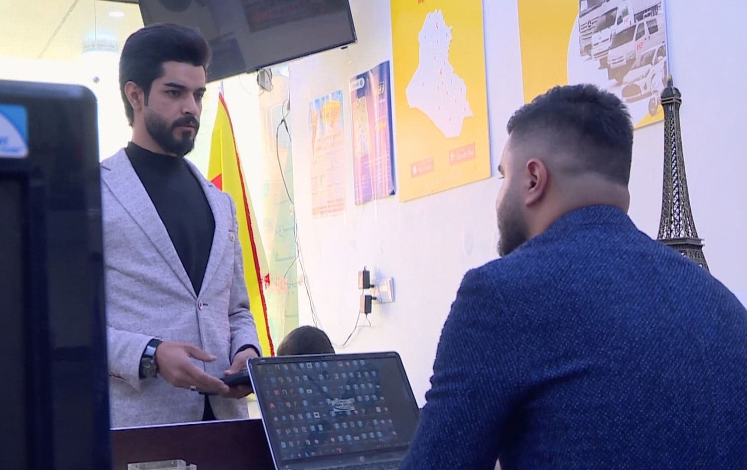 Mikail Kamal (left) visits a travel agency in Soran on October 28, 2021 to ask about a flight to Belarus. Unemployed, he is hoping to migrate to Europe. Photo: screengrab/Rudaw